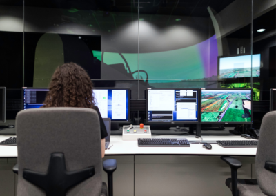 Engineer monitoring multiple screens in a control room with a large panoramic display, illustrating a computer-aided engineering project