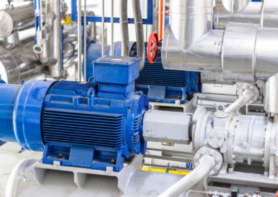 Industrial blue electric motor connected to compressor piping, illustrating a high-performance synchronous compressor motor development project
